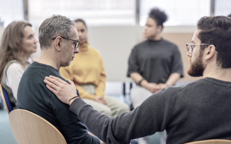 Man comforting a client in group therapy
