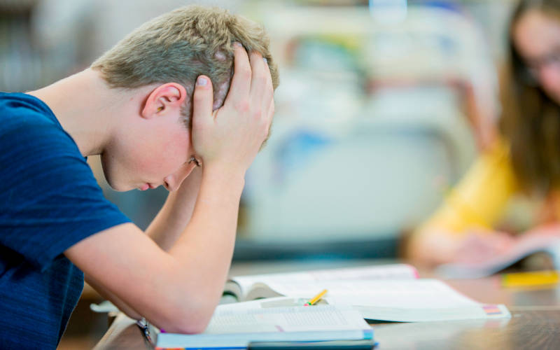 A teen struggling with mental health, while sitting at a desk in school.