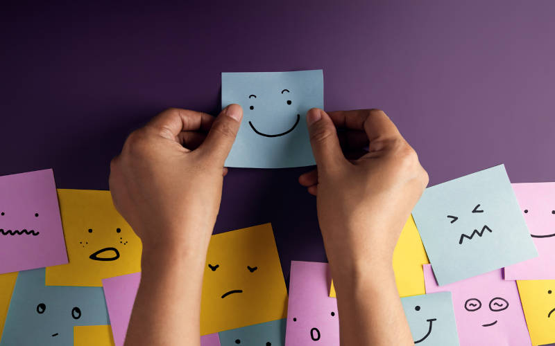 A photo of a bunch of sticky notes with different faces, an abstract portrait showing sings your teen may need mental health treatment.