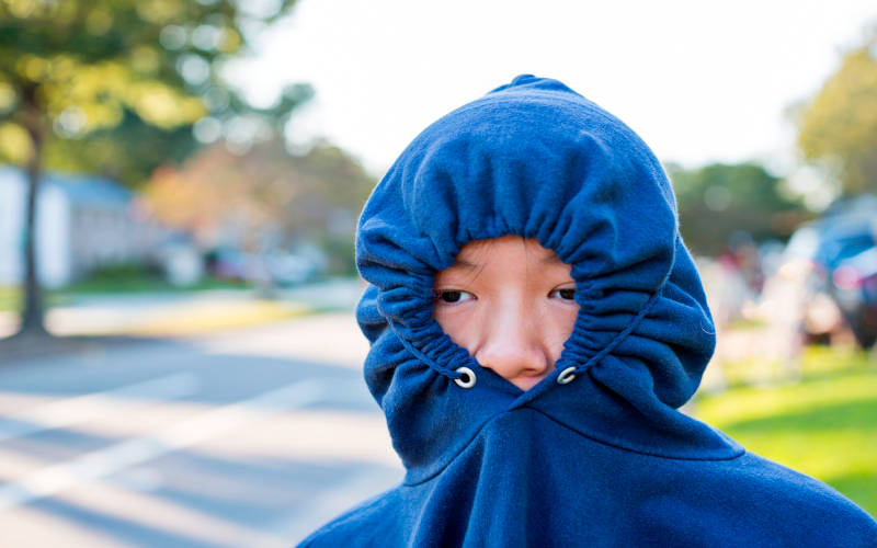 A withdrawn teen with their face hiding in their hoodie.