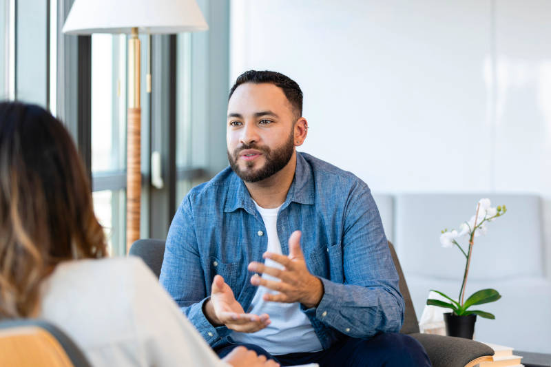 A man in a therapy session learning about Full-Day Treatment (PHP) vs. Half-Day Treatment (IOP).