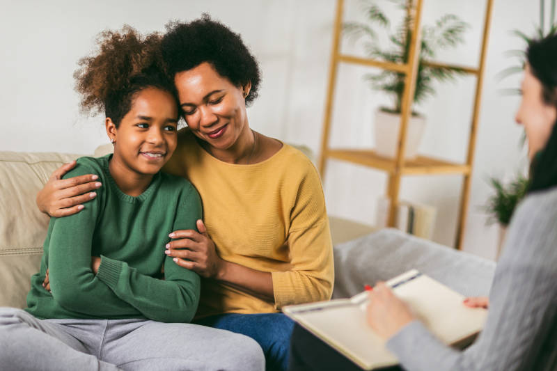 A mother supporting her child during a mental health treatment therapy session.